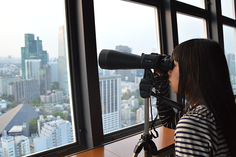 東京タワー展望台から超高倍率双眼鏡を覗いてる。
